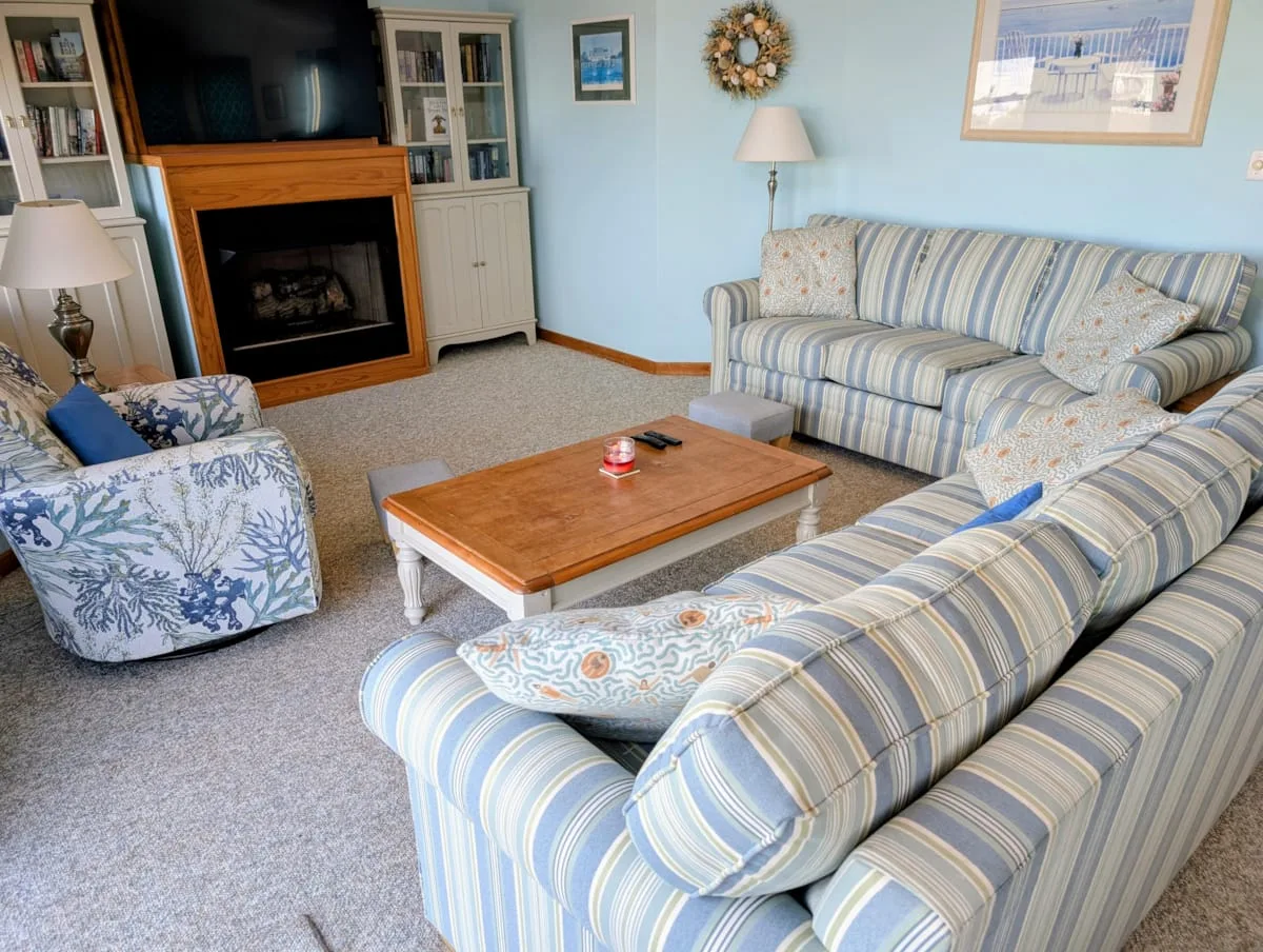 Una sala de estar con asientos a rayas alrededor de una mesa de centro de madera.