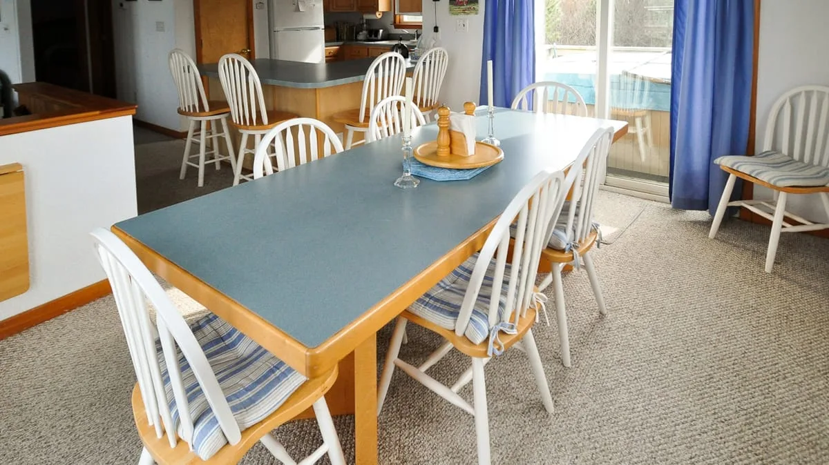 Un comedor con una mesa larga y asientos blancos.