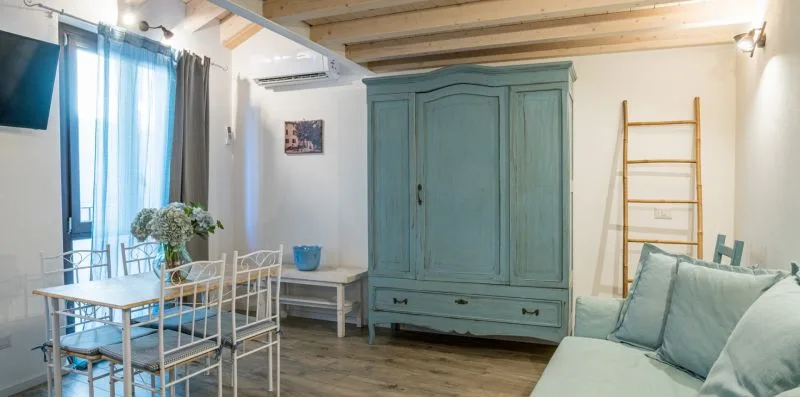 A bright bedroom with a large teal wardrobe and pale seating.