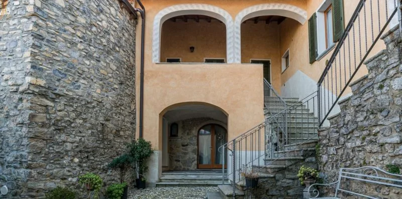 Un patio de piedra con una entrada en arco y una escalera exterior.