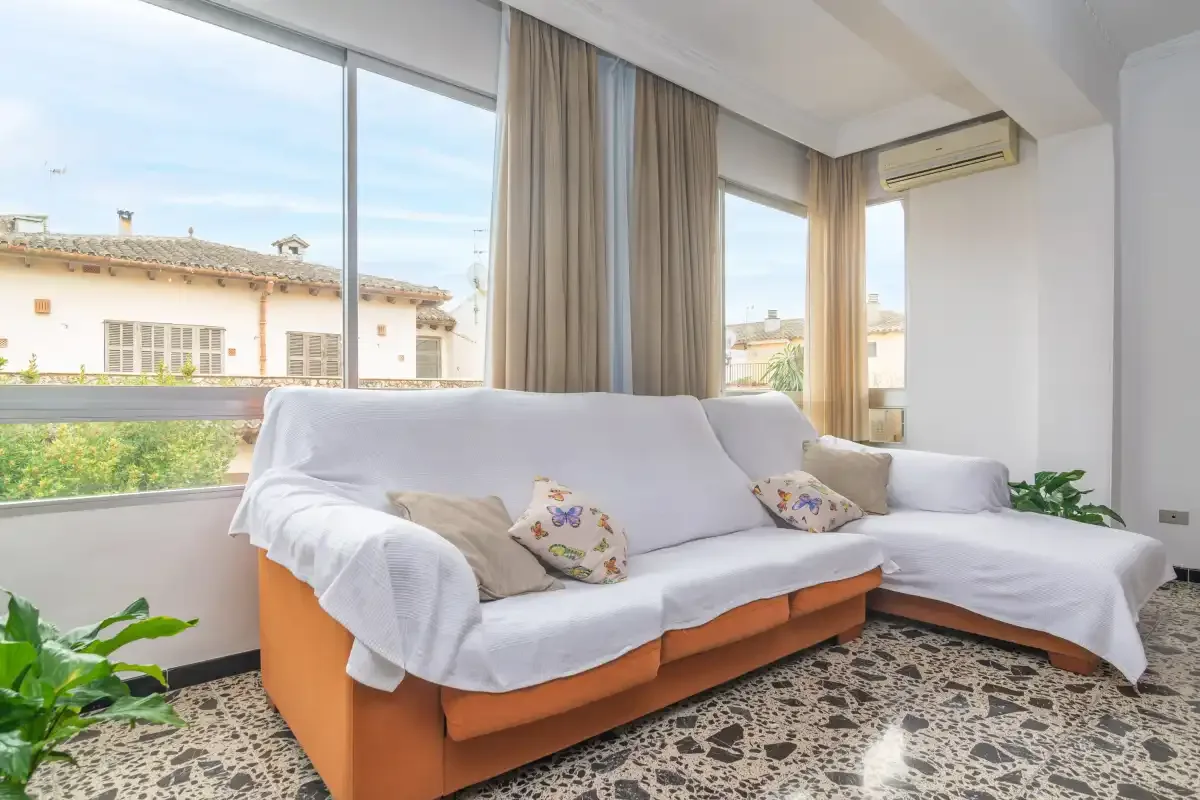 A bright living room with seating beside large windows.