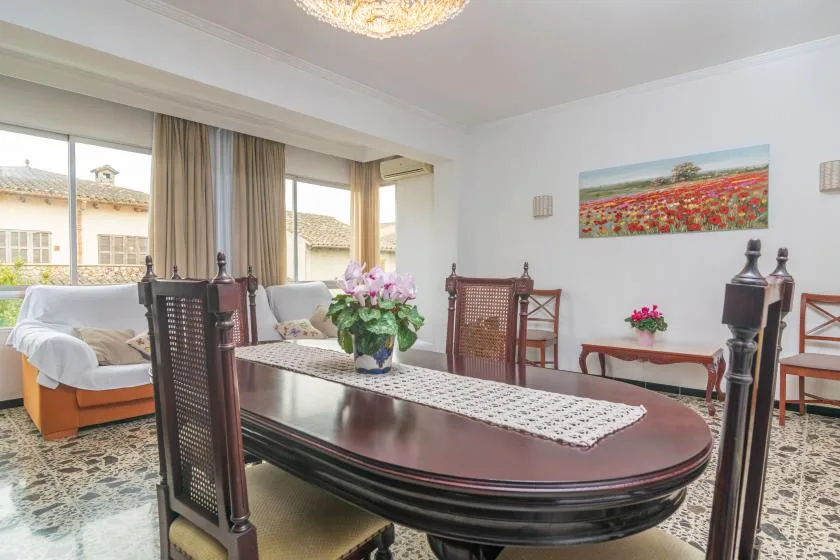 A dining room with a long table, chairs, and large windows.