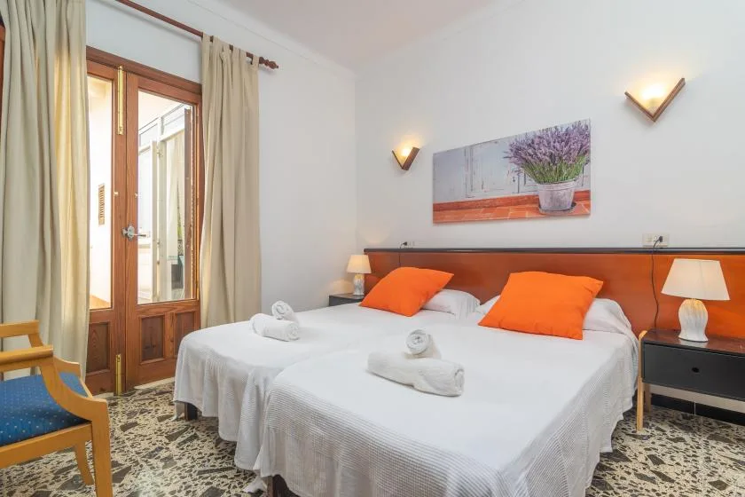 A bedroom with two beds, orange cushions, and a wooden headboard.