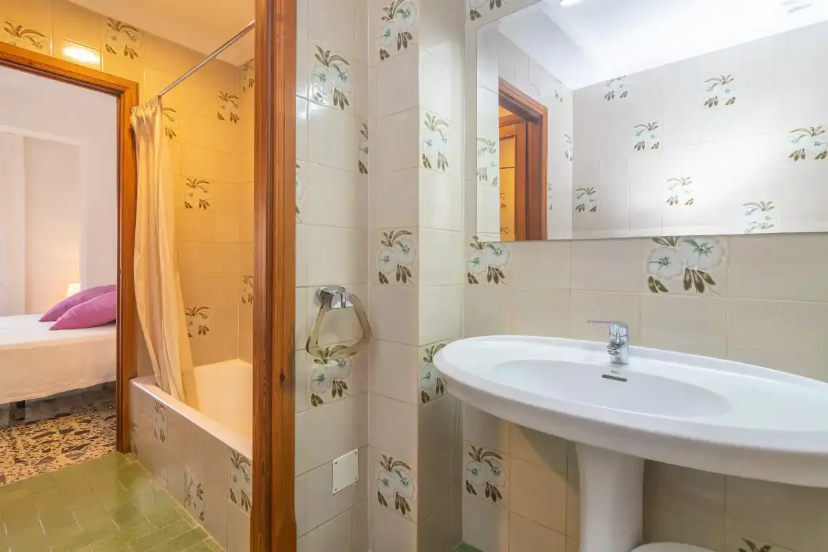 A tiled bathroom with a bathtub, sink, and mirror.