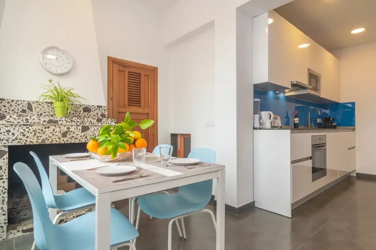 A bright kitchen and dining area with a table and blue seating.