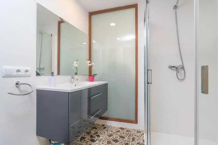 A bright bathroom with a vanity, mirror, and glass shower.