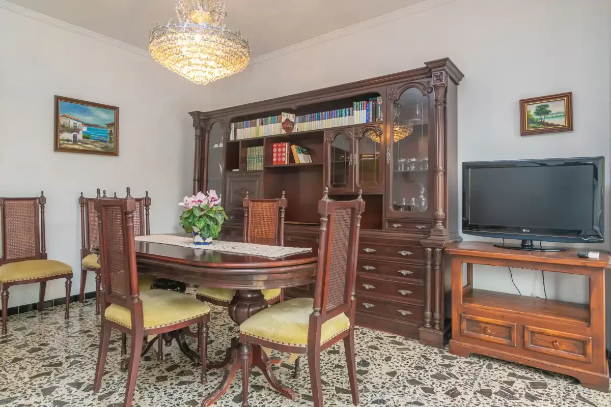 A dining room with a wooden table, chairs, and a large display cabinet.