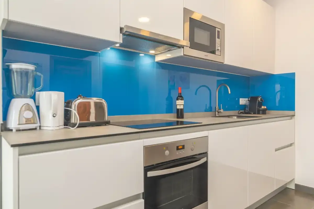 A modern kitchen with white cabinets and a blue backsplash.