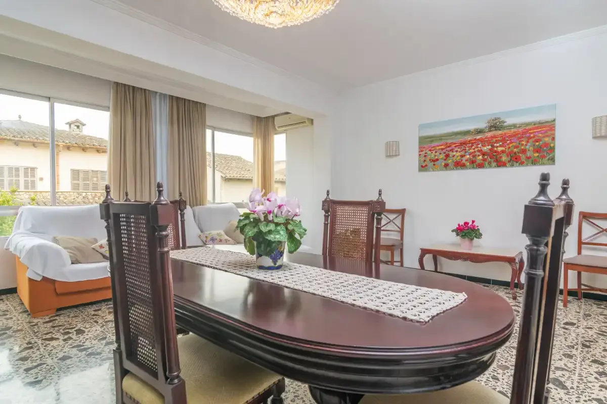 A dining room with a long table set with a runner and flowers.