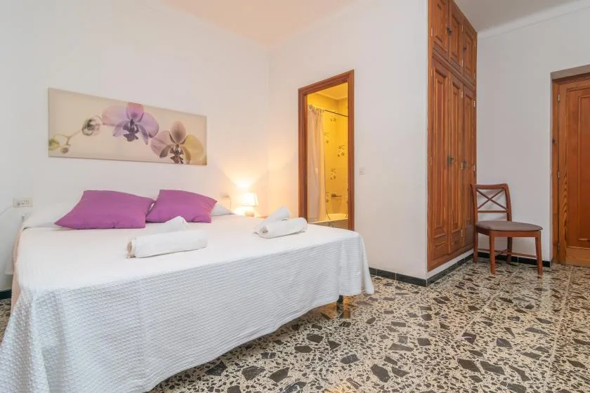 A bedroom with a neatly made bed and purple pillows.