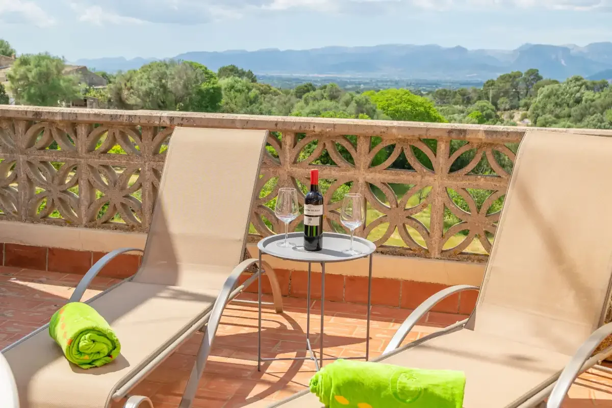 A sunny terrace with reclining seating and a view of the surrounding hills.