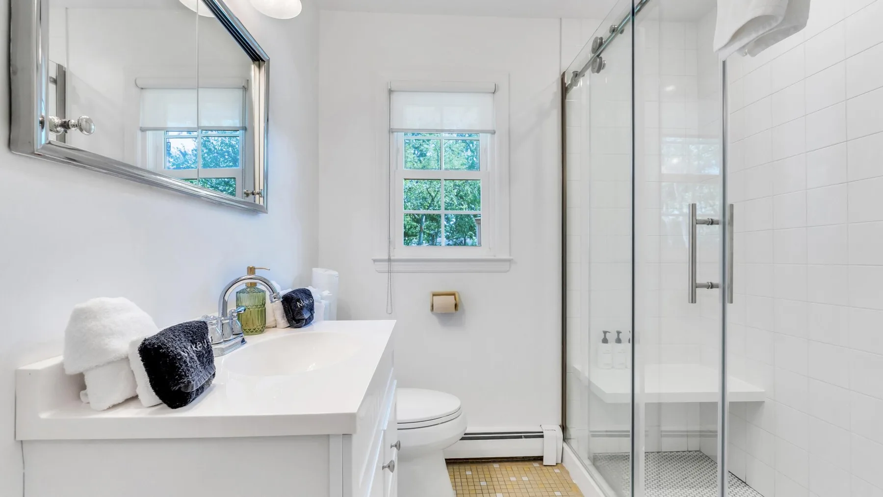 A bright bathroom with a sink, toilet, and glass shower.