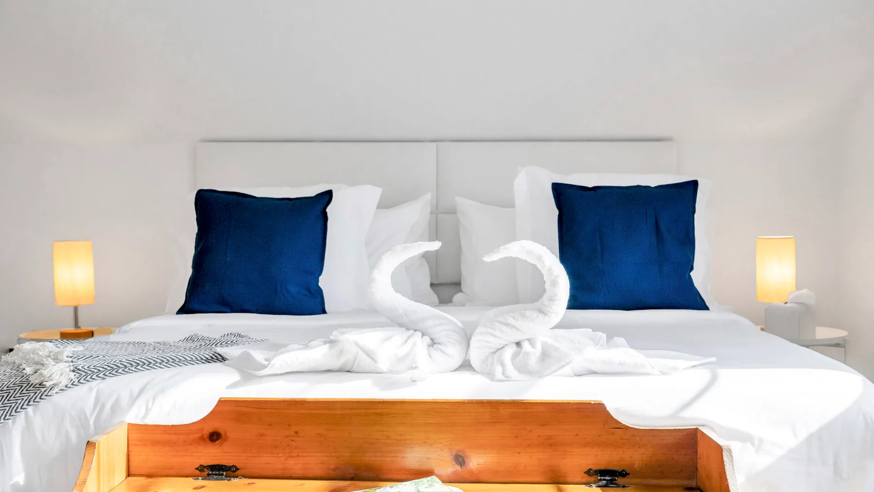 A bedroom with a neatly made bed and towels arranged in a decorative shape.