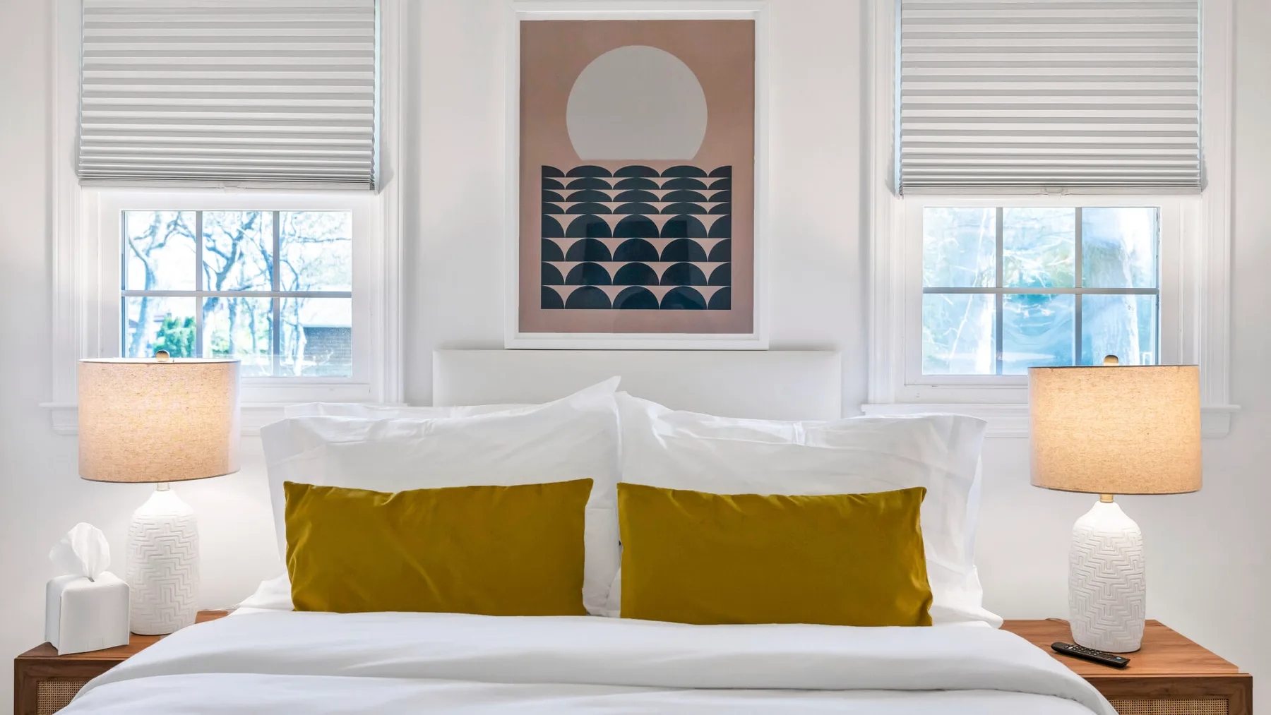 A bright bedroom with a neatly made bed and mustard-colored pillows.