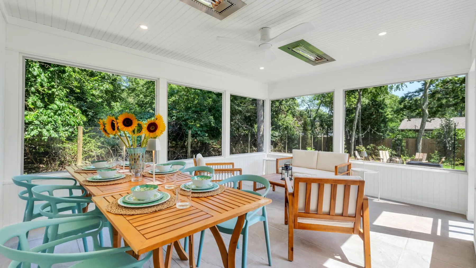 A bright sunroom with a dining table and large windows overlooking greenery.