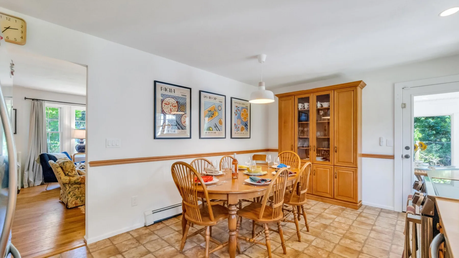 A dining room with a wooden table, chairs, and a glass-front cabinet.