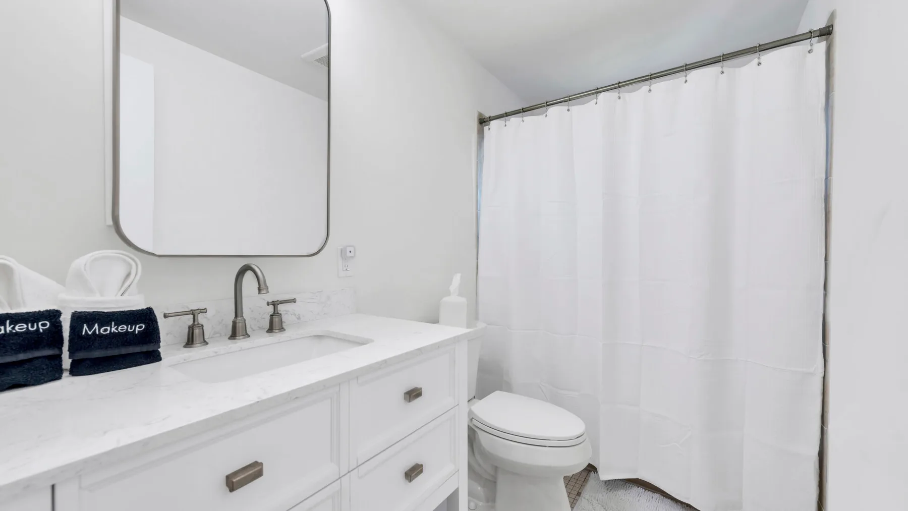 A bright bathroom with a white vanity and a shower curtain.