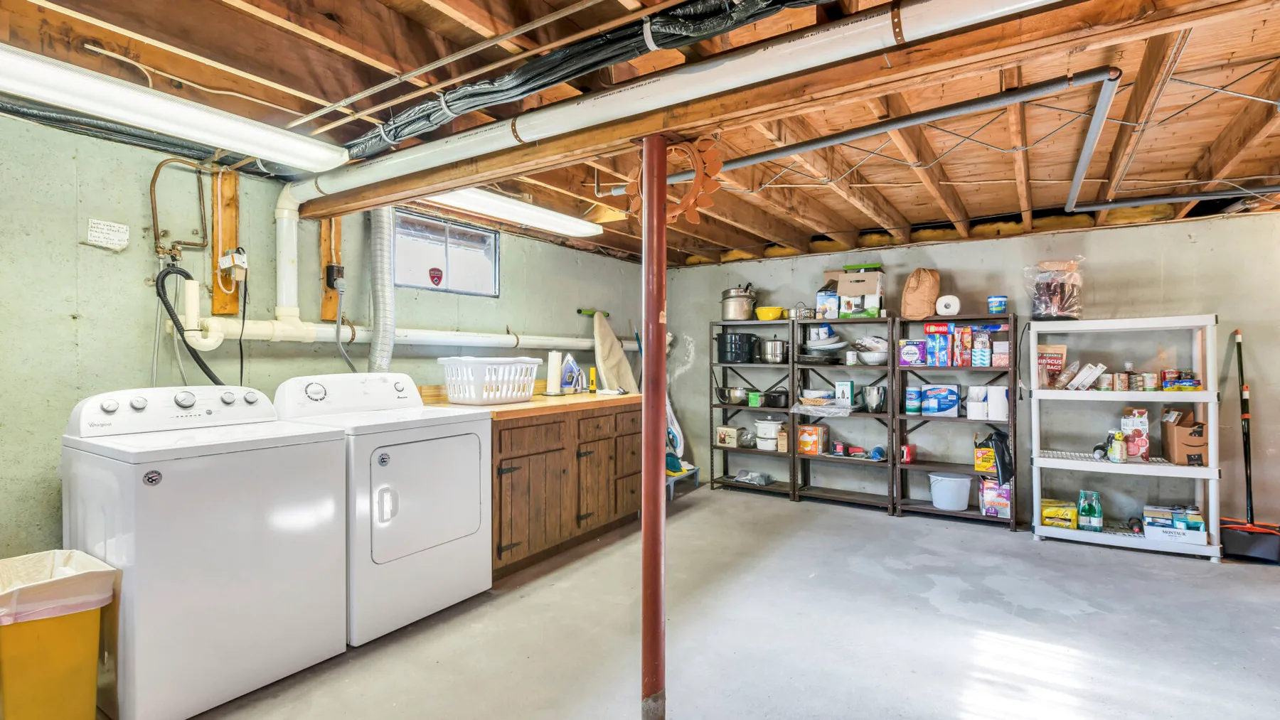 A basement laundry and storage area with appliances and open shelving.