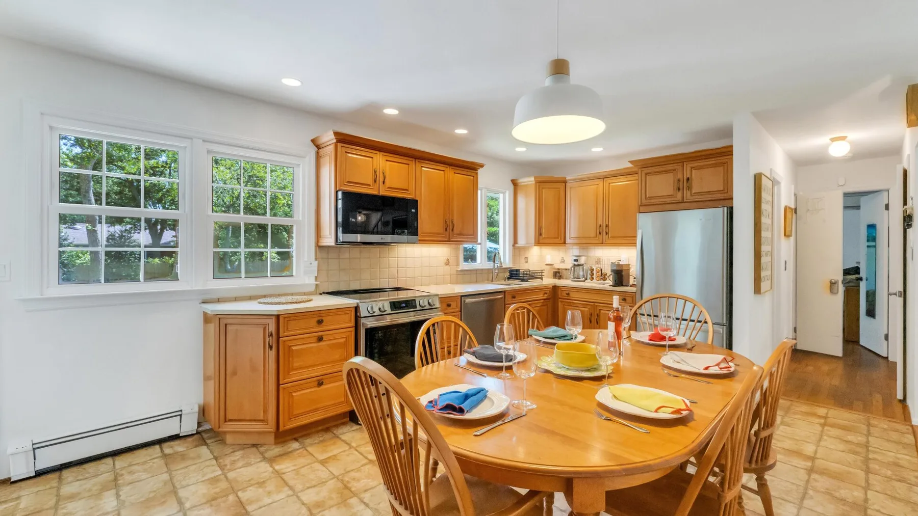 A bright kitchen and dining area with wooden cabinets and a set dining table.