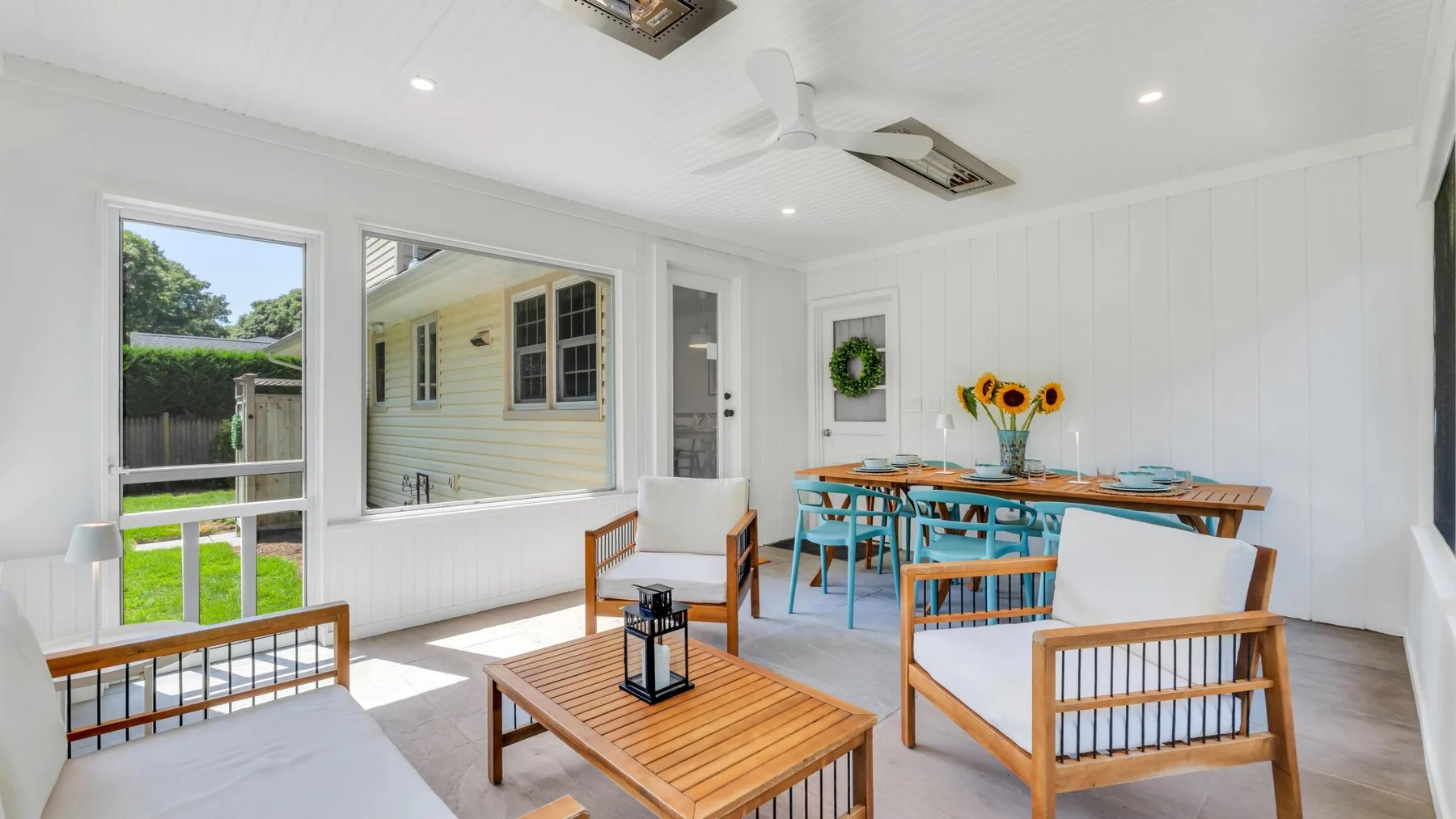 A bright sunroom with wooden seating and a dining table.