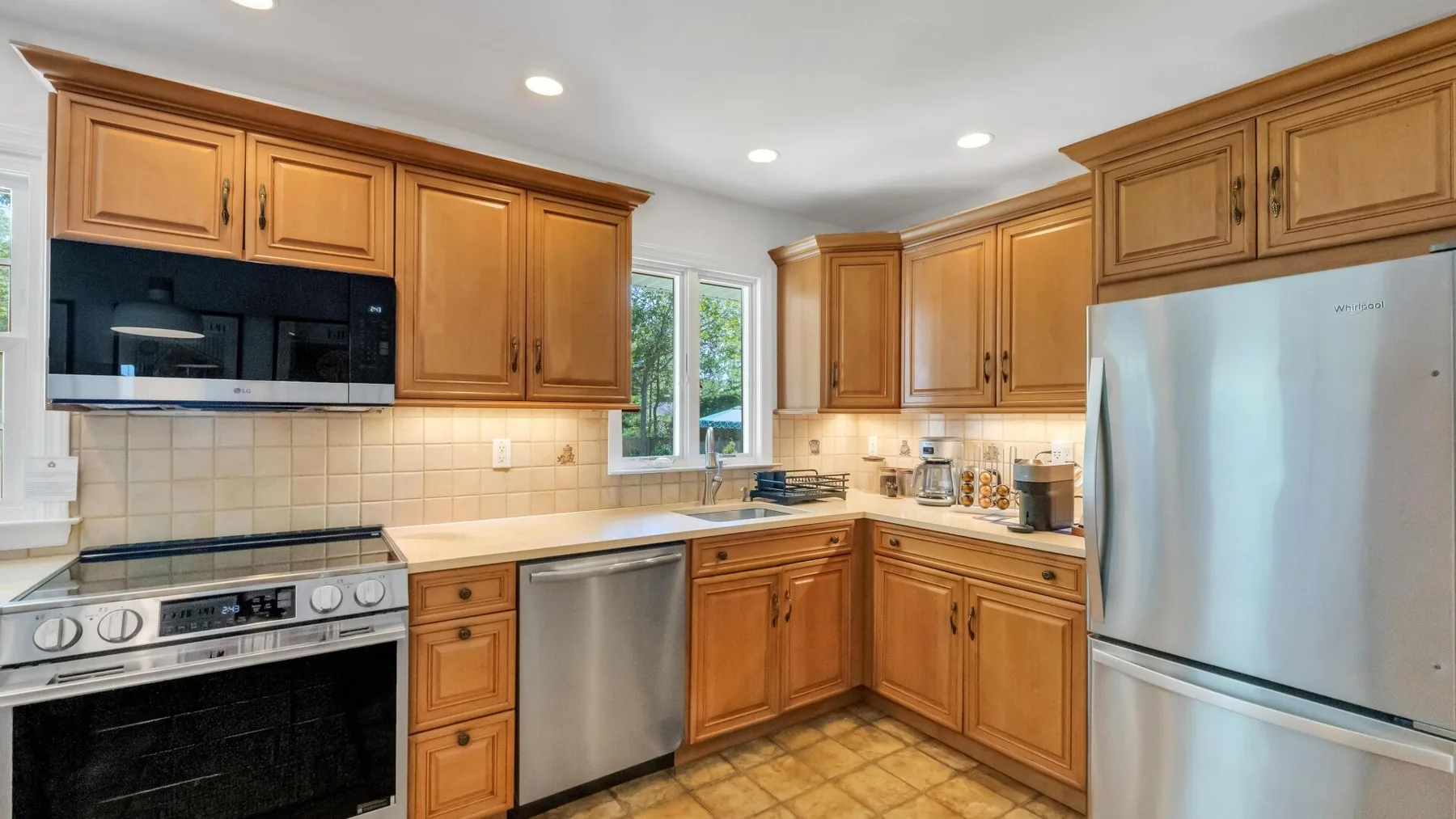 A kitchen with wooden cabinets, stainless steel appliances, and tiled flooring.
