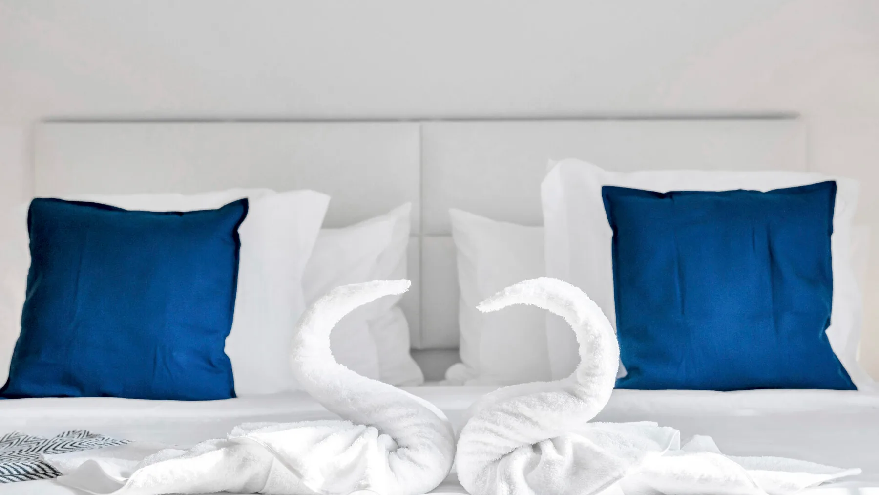 A bedroom scene with white towels folded into swan shapes on a bed.