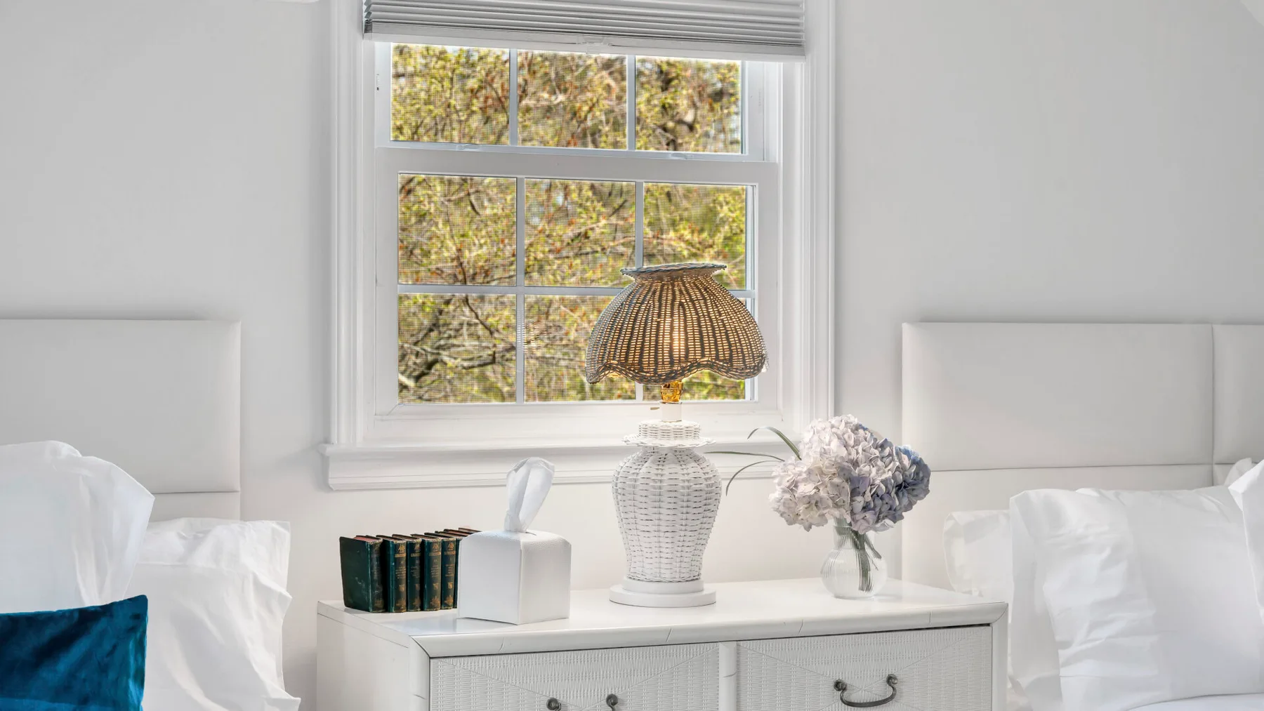 A bright bedroom with a window, bedside table, and neatly made bed.
