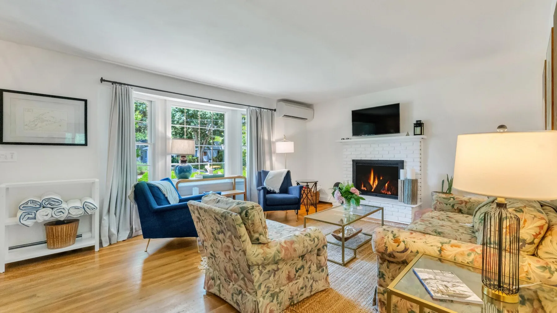 A living room with seating arranged around a glass coffee table and fireplace.