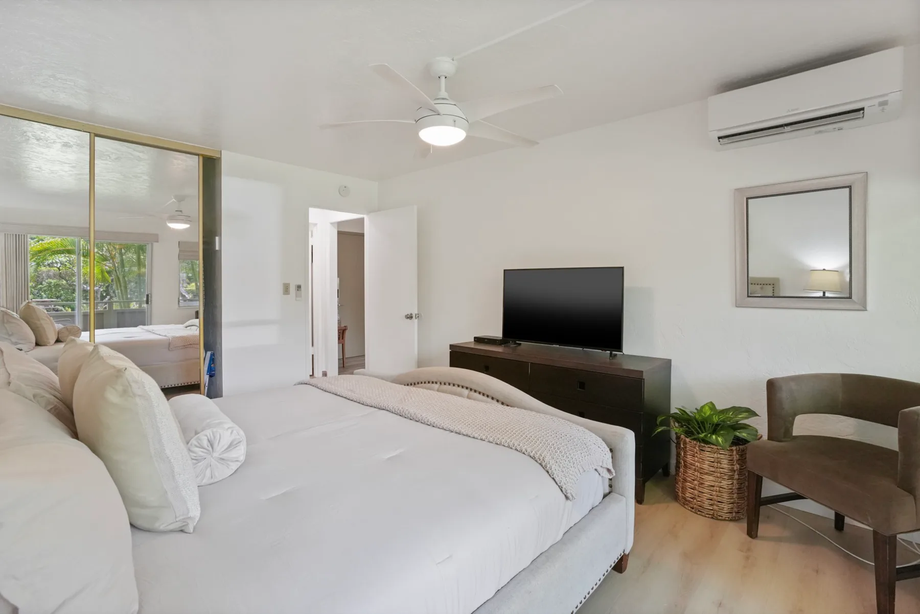 Un dormitorio luminoso con una cama grande, televisor y asientos.