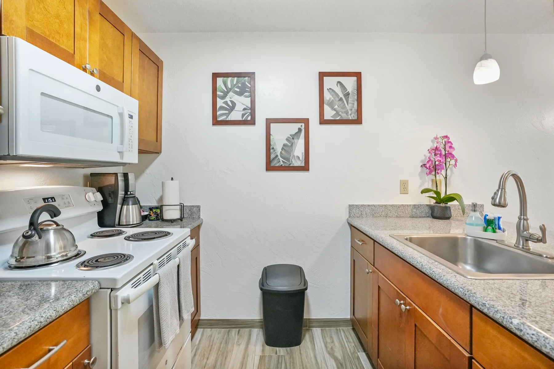 Una cocina compacta con estufa, microondas y fregadero en lados opuestos.