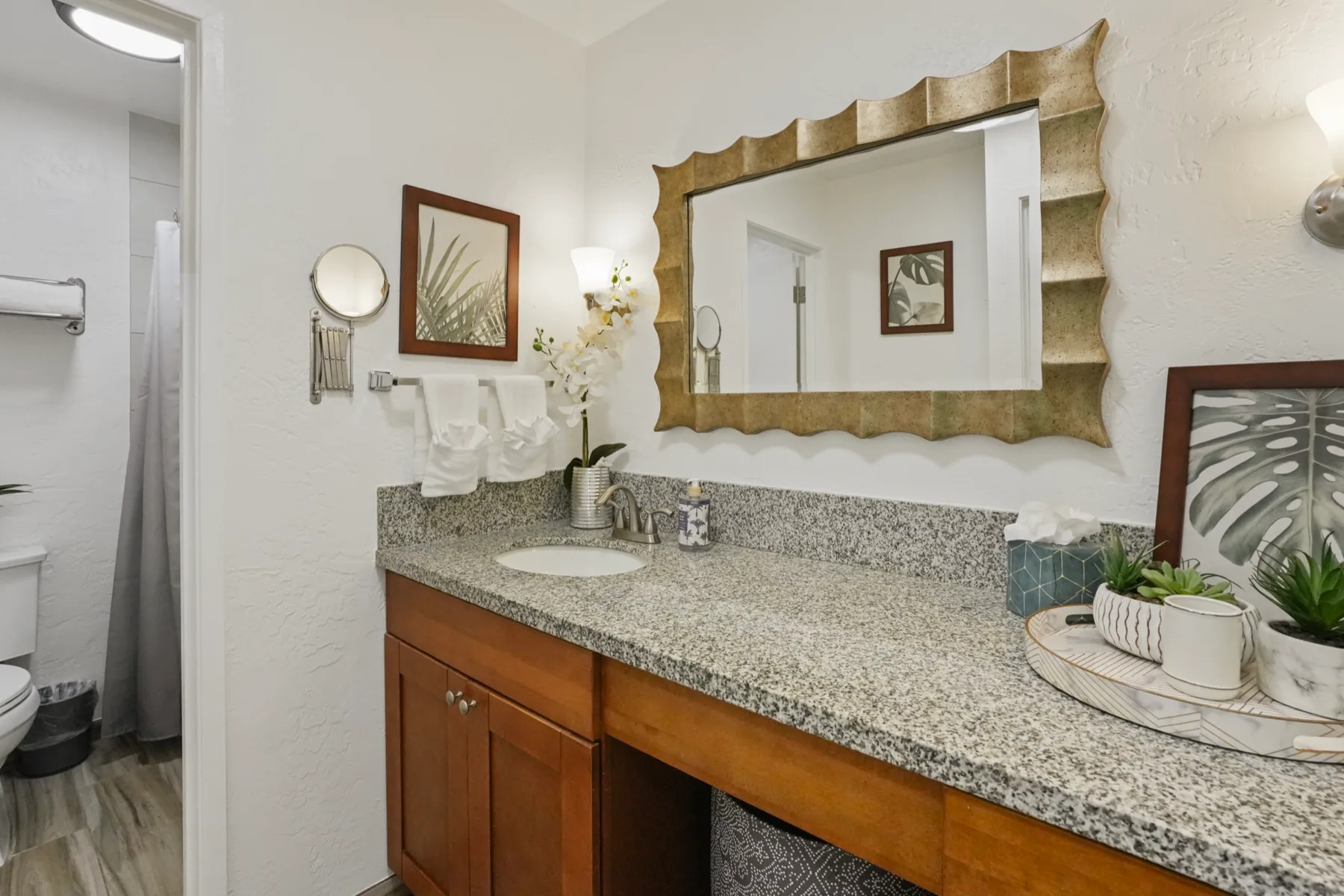 Un tocador de baño con una encimera larga, lavabo y un gran espejo enmarcado.