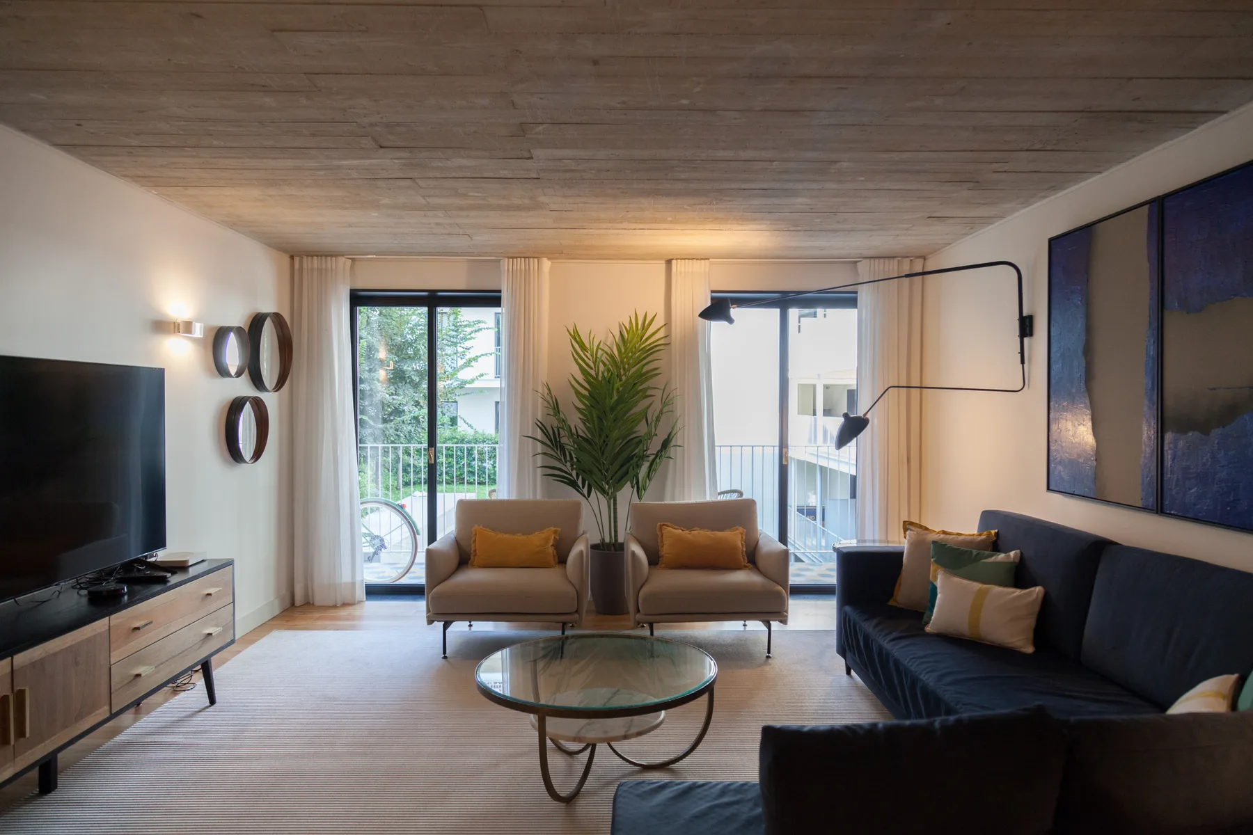 Sala de estar con asientos, una mesa de centro y grandes ventanas.