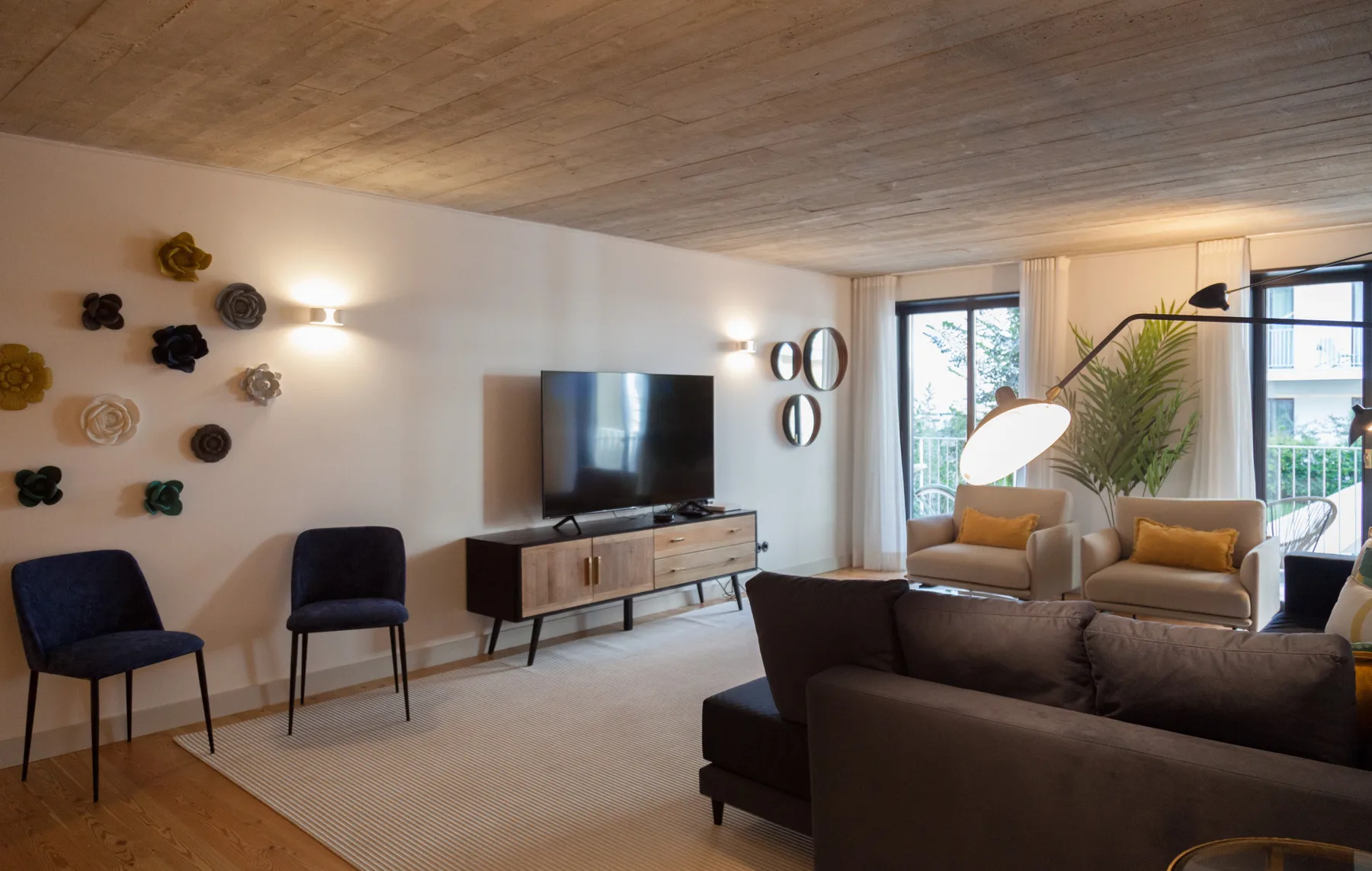 Una sala de estar con asientos, un televisor y ventanas que dan a un balcón.