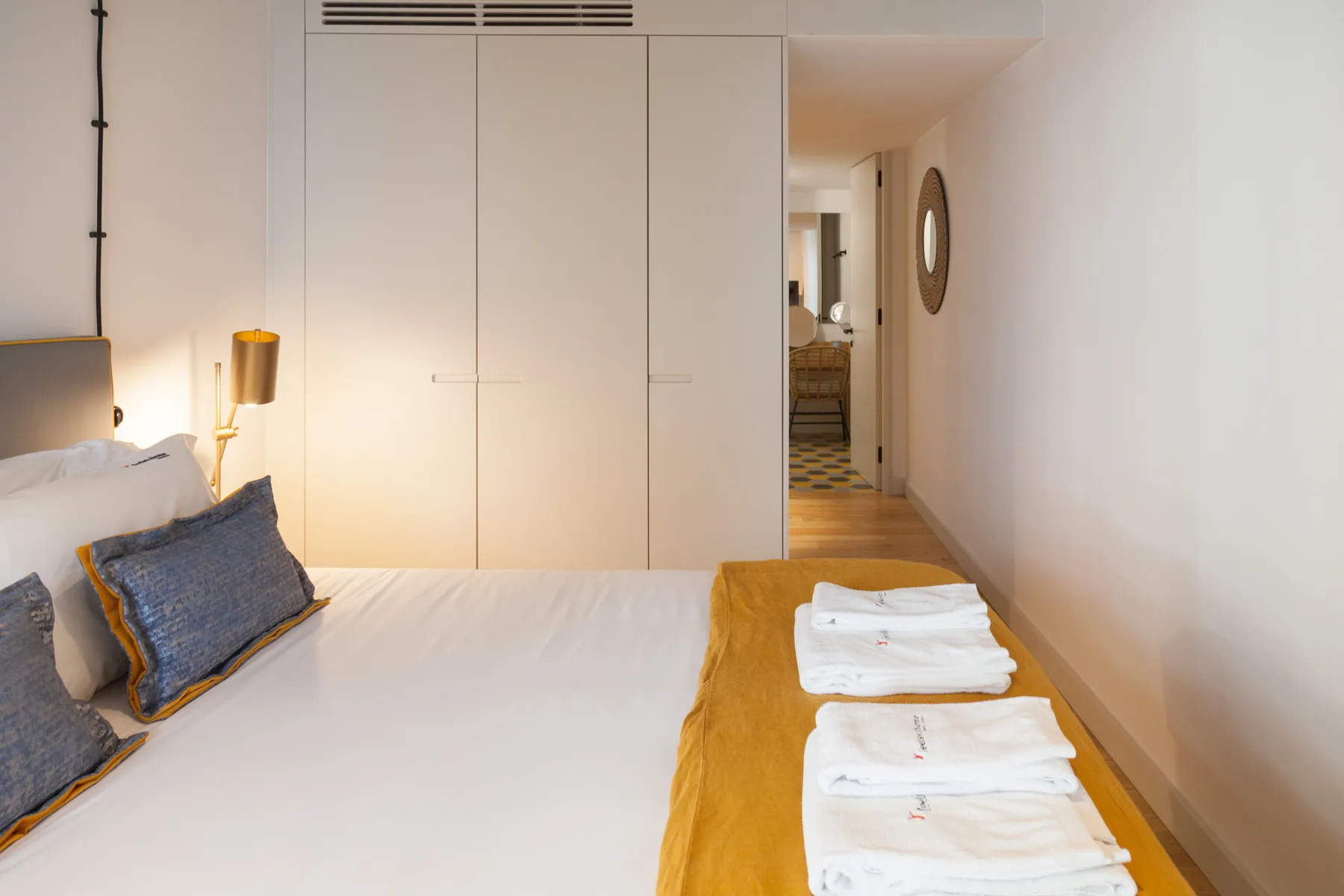 Dormitorio con una cama y toallas dobladas sobre un banco de madera.