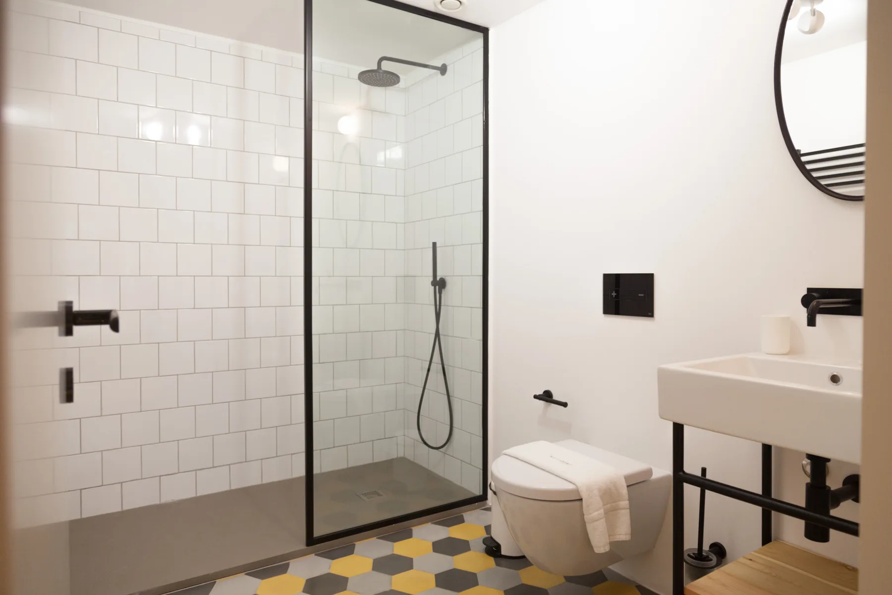 Un baño luminoso con ducha de cristal, inodoro y lavabo.
