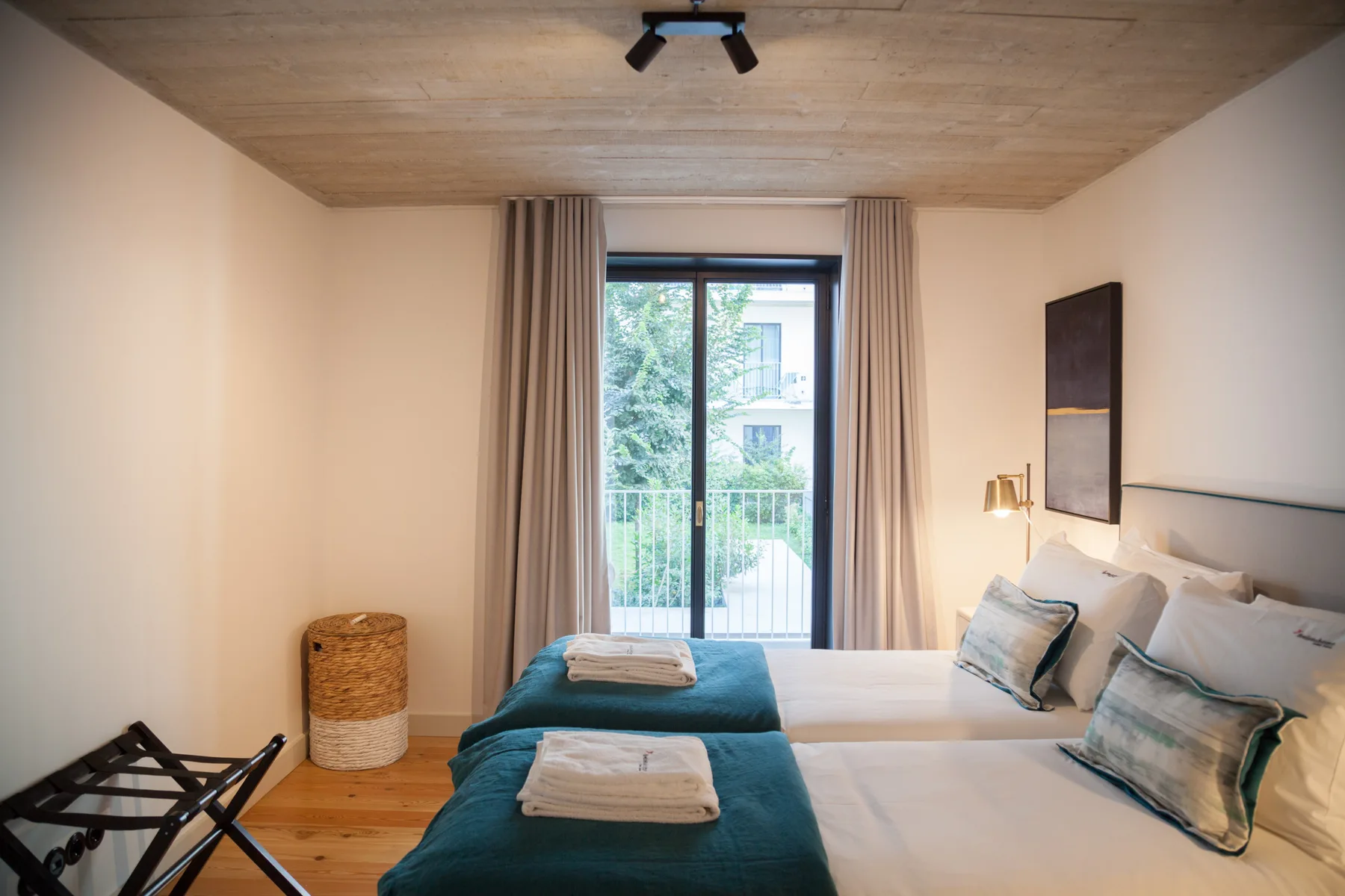 Un dormitorio con dos camas junto a una puerta de cristal que da al balcón.