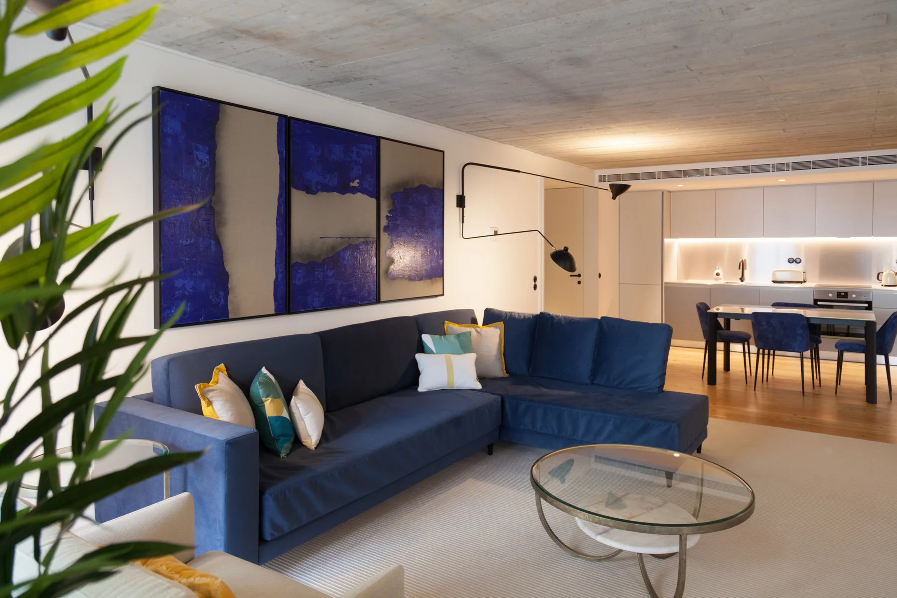 Sala de estar con asientos azules y un comedor al fondo.