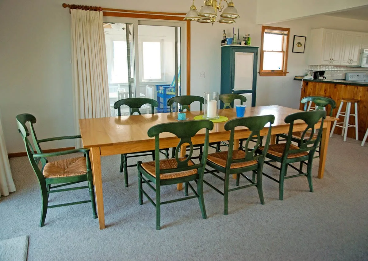 Un comedor con una mesa larga de madera y asientos verdes.