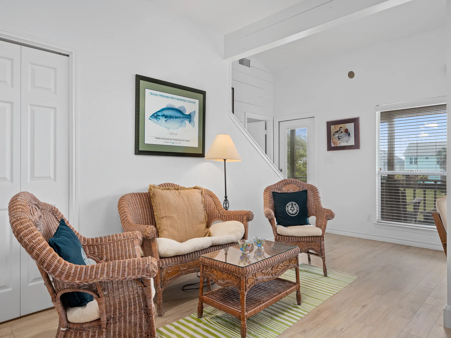 A bright living room with wicker seating, a coffee table, and framed wall art.