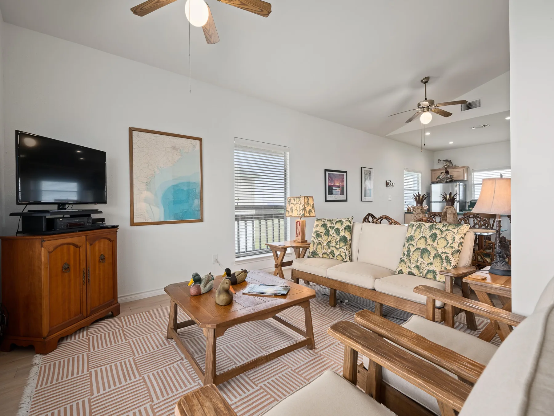 A bright living room with a television, patterned seating, and a wooden coffee table.