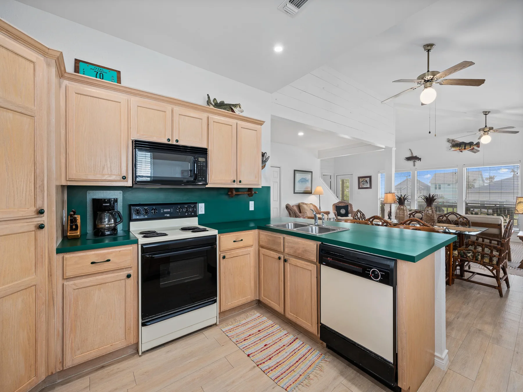 An open kitchen with green countertops and a dining area beyond.