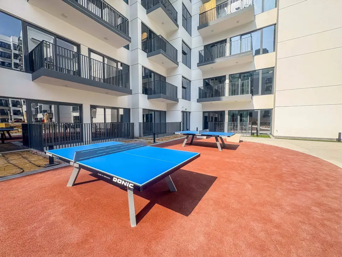 An outdoor recreation area with blue table tennis tables in a courtyard.