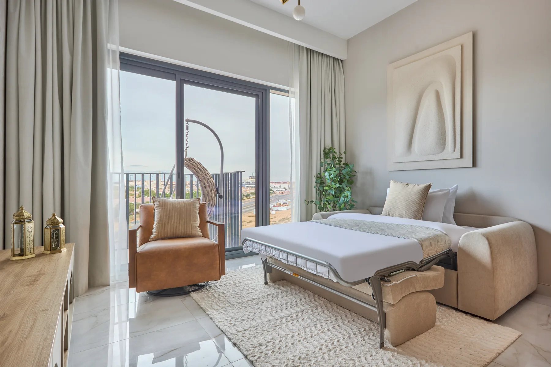 A bright bedroom with a large window, a bed, and a cushioned chair.