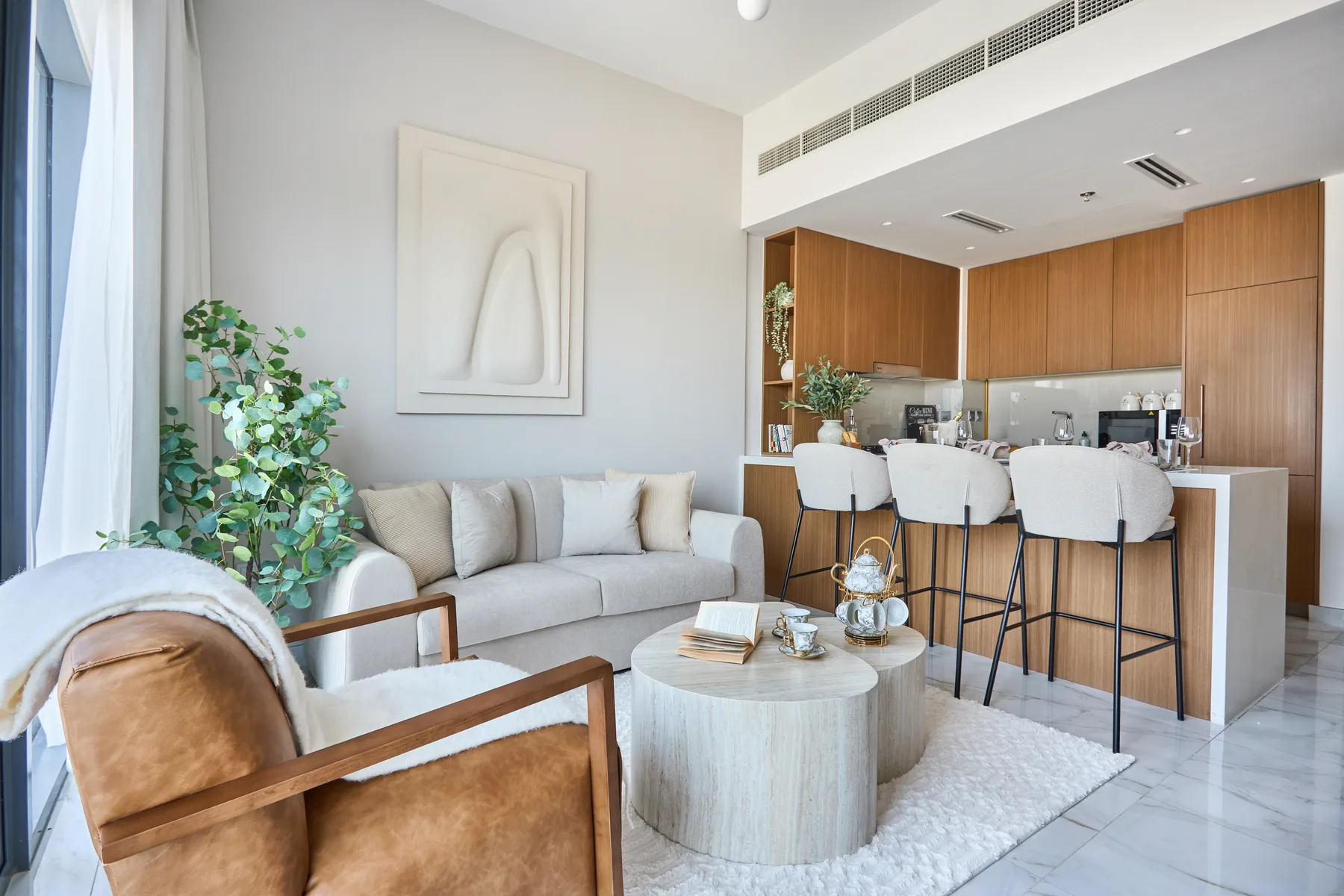 A bright living area opens onto a kitchen, with seating around a low coffee table.