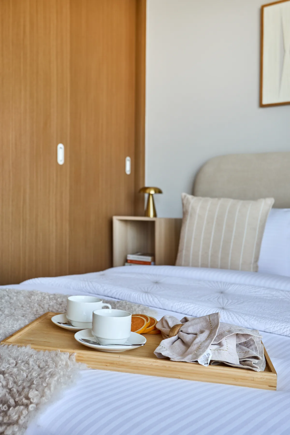 A bedroom with a neatly made bed and a tray holding cups.