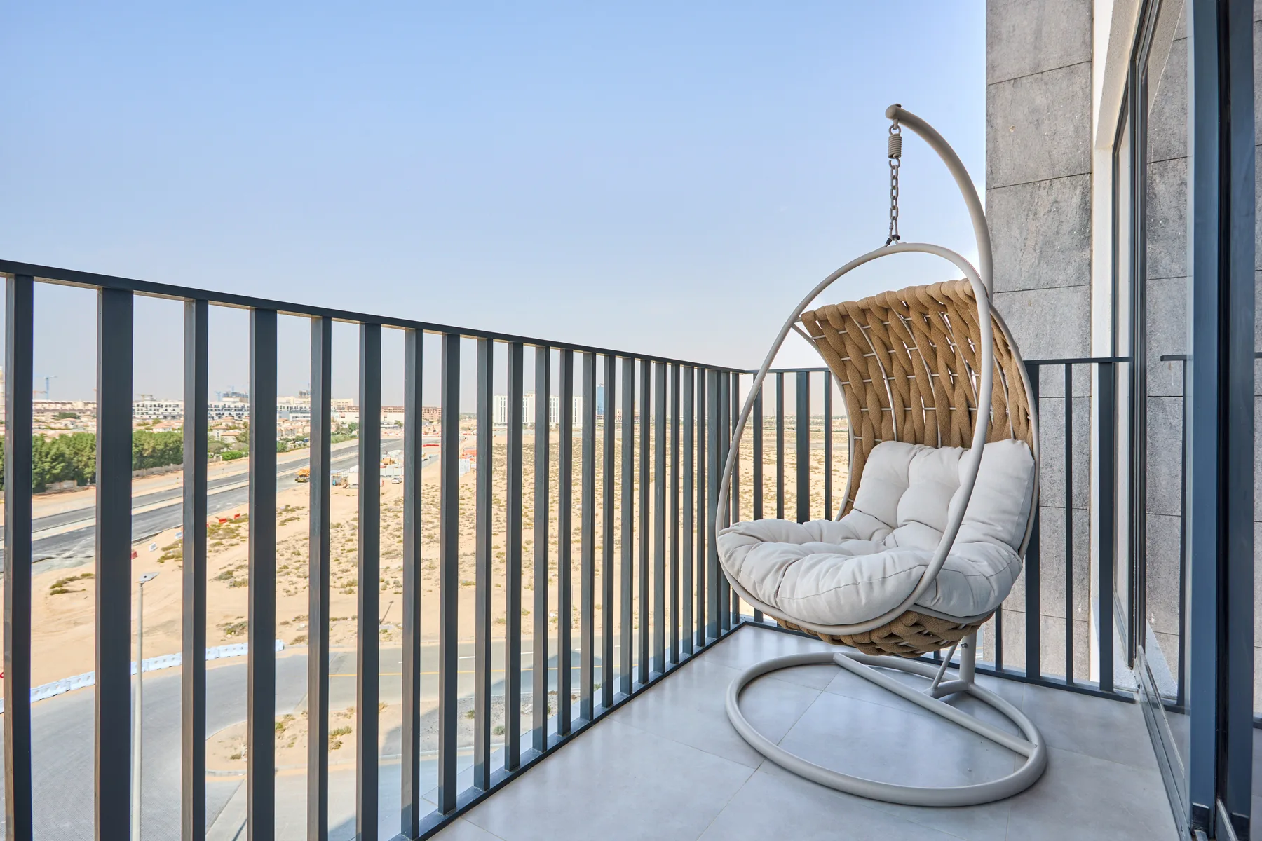 A balcony with a hanging cushioned seat and a view of the surrounding landscape.