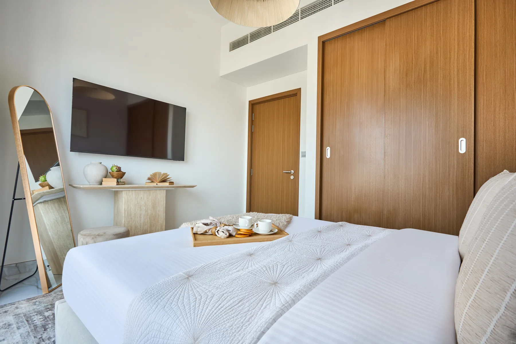 A bedroom with a neatly made bed and a television mounted on the wall.