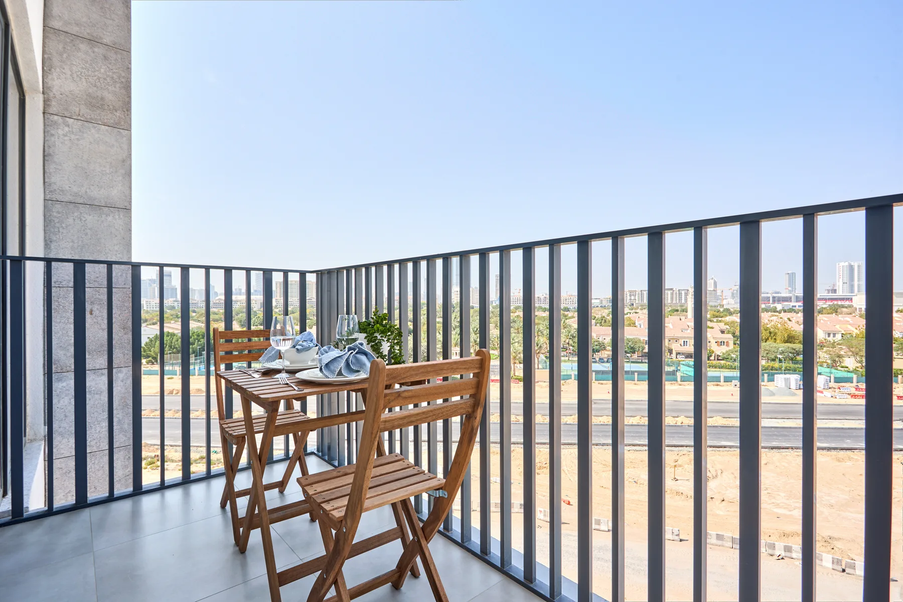 A balcony with wooden seating and a table overlooks the surrounding city.