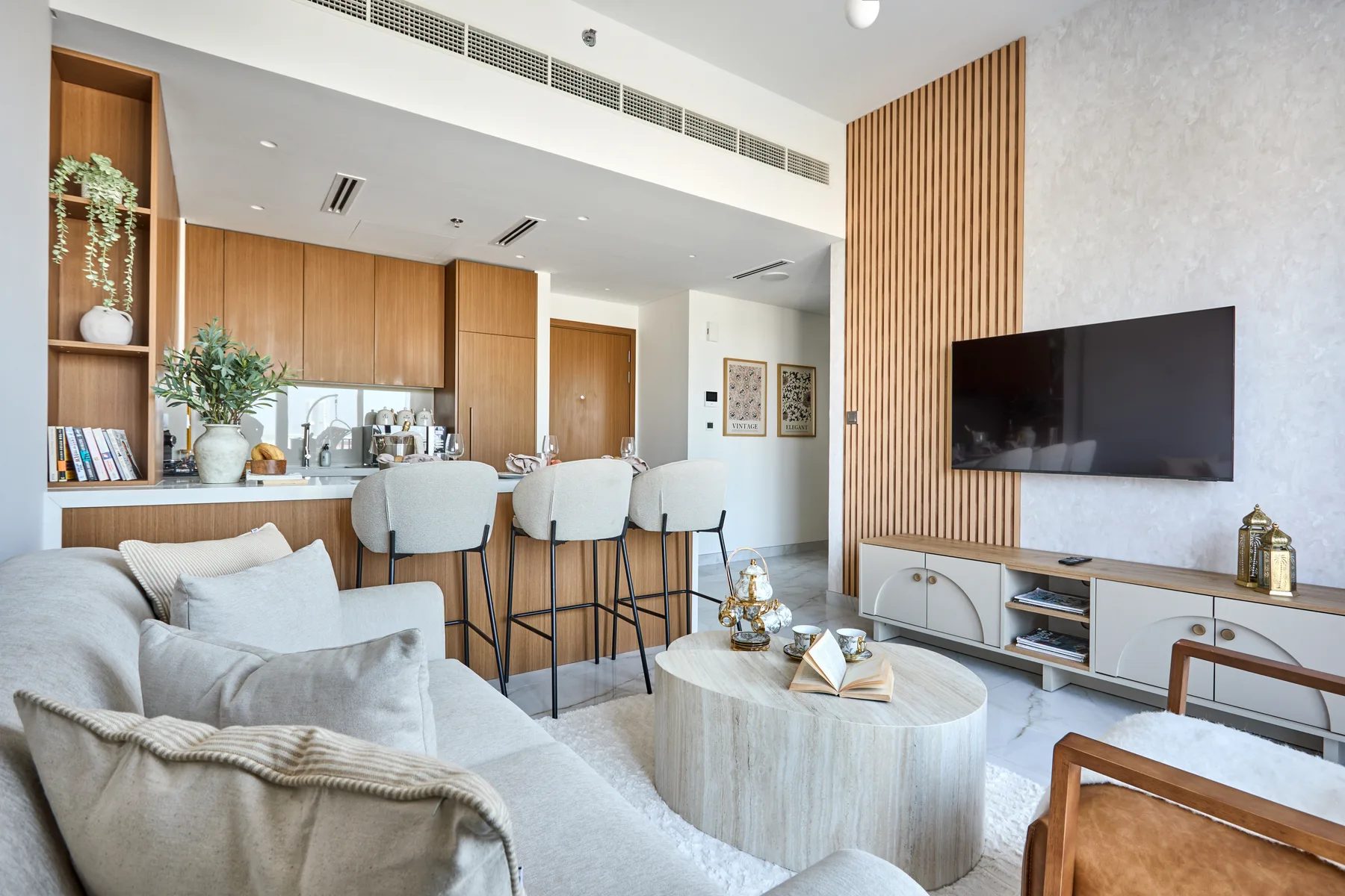 An open-plan living room and kitchen with a dining counter and television.