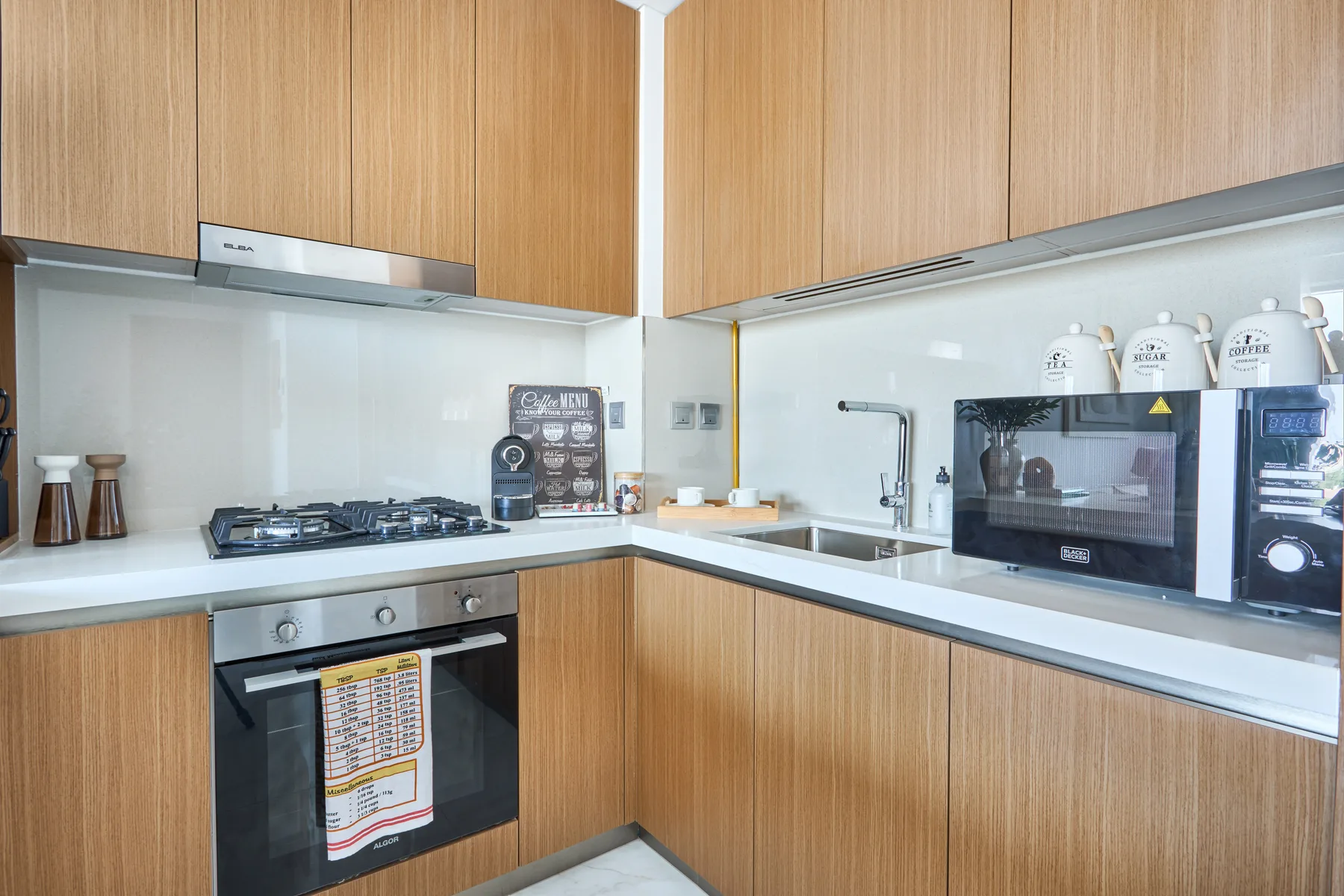 A modern kitchen with wood cabinets, a cooktop, and a built-in oven.